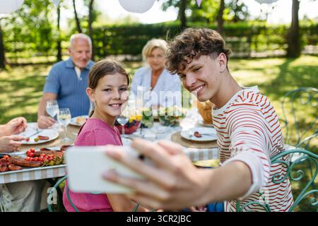 Familientreffen zum Grillen im Sommergarten, Selfie machen. Stockfoto