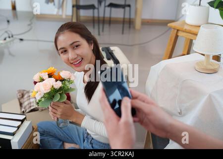 Lächelnde Frau, Die Blumen Hält, Während Der Partner Fotos Macht Stockfoto