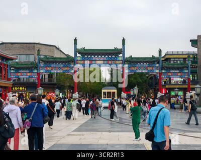 Peking, China - 15. September 2025 : Eine lebhafte Szene auf der Qianmen Straße in Peking, mit einem wunderschönen traditionellen Torbogen, einer historischen Straßenbahn und cr Stockfoto