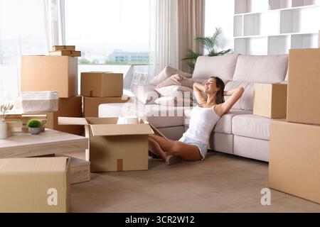 Glückliche Frau zieht sich aus und sitzt auf dem Boden Stockfoto