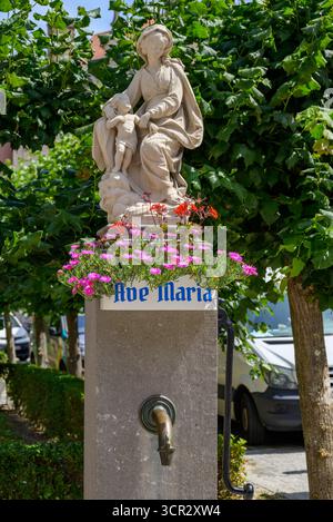 Eine religiöse Statue der Jungfrau Maria mit Blumen und einem Wasserauslauf vor der Kirche unserer Lieben Frau in der historischen Altstadt von Brügge, Belgien am 17. Juli Stockfoto