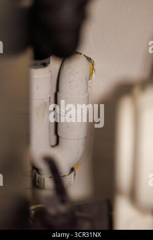 Nahaufnahme von weißen PVC-Abflussrohren mit Verbindungen und Armaturen im Versorgungsraum. Stockfoto