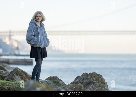 Eine junge Frau, die auf Felsen neben dem Fluss steht Stockfoto