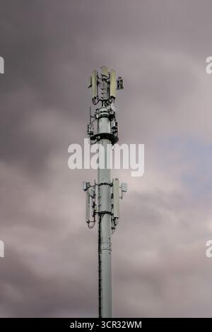 Telekommunikationsturm mit Antennen gegen bewölkten Himmel Stockfoto