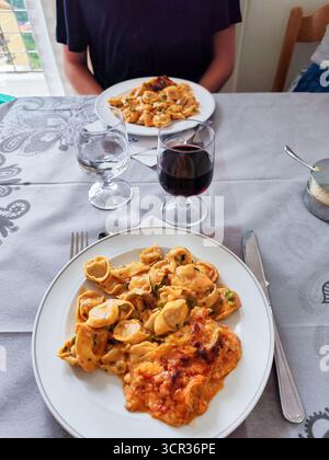 Tortelloni Bolognesi Lasagne und ein Glas Wein. Mittagessen für zwei Personen in einem italienischen Restaurant. Ein Teller mit Essen auf dem Tisch. Stockfoto