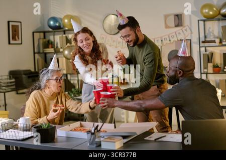Verschiedene Gruppe von jungen Erwachsenen und älteren Frauen, die drinnen Geburtstag feiern Stockfoto