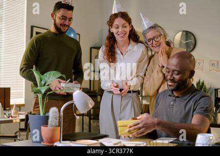 Verschiedene junge Erwachsene und ältere Kollegen feiern Geburtstag im Büro Stockfoto