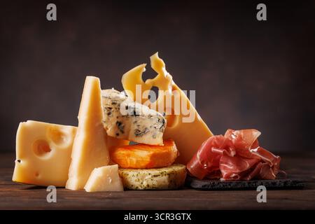 Verschiedene Käsesorten in verschiedenen Formen und Texturen, die zusammen auf einer rustikalen Oberfläche präsentiert werden Stockfoto