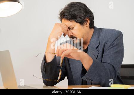 Müde Erwachsene Mann fühlen Schmerzen Augenanstrengung in der Hand Brille reiben trockene gereizte Augen müde von der Computerarbeit. Das Office-Syndrom-Konzept. Stockfoto