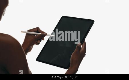 Person, die ein Tablet und einen Stift verwendet, um Technologie, Kreativität und Produktivität zu veranschaulichen. Moderne digitale Tools, Bildschirminteraktion und minimalistisches Design Stockfoto