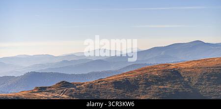 Ein Panoramablick auf mehrschichtige Bergkämme, die in sanftes Licht getaucht sind Stockfoto