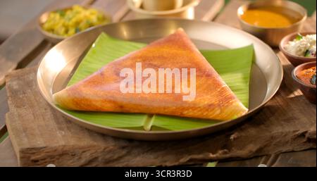 Masala Dosa, Mysore Dosa, Rava Dosa und Paper Dosa werden heiß mit Chutney und Sambar serviert – authentisches südindisches Frühstück, das für seine knusprigen Speisen geliebt wird Stockfoto
