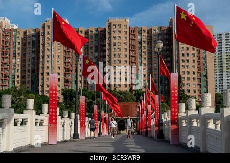 Eine allgemeine Ansicht, die Menschen zeigt, die am 29. September 2025 in Hongkong auf einer Brücke an chinesischen Nationalflaggen vorbeilaufen. (Foto von Vernon Yuen/Nexpher Images) Stockfoto