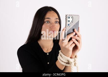 Die Frau hält ein Smartphone in der Hand und scheint auf den Bildschirm zu schauen. Stockfoto