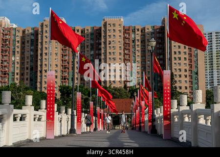 Hongkong, Hongkong. September 2025. Eine allgemeine Ansicht, die Menschen zeigt, die am 29. September 2025 in Hongkong auf einer Brücke an chinesischen Nationalflaggen vorbeilaufen. (Credit Image: © Vernon Yuen/Nexpher Images via ZUMA Press Wire) NUR REDAKTIONELLE VERWENDUNG! Nicht für kommerzielle ZWECKE! Stockfoto