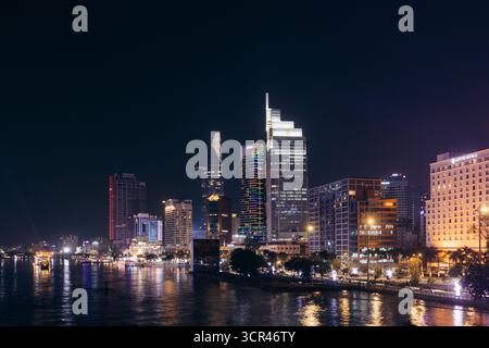 Lebhafte Skyline von Ho Chi Minh City bei Nacht mit beleuchteten Wolkenkratzern, die sich auf dem Wasser spiegeln. Ho-Chi-Minh-Stadt Vietnam Stockfoto