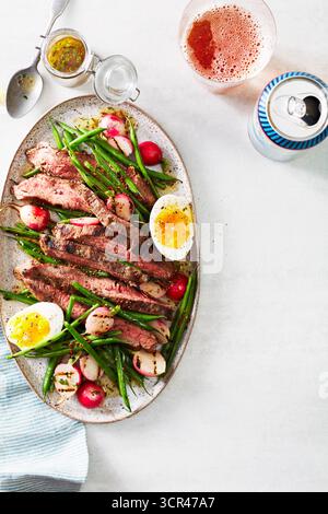 Steaksalat mit gegrillten Erbsen, Rettich und Ei auf ovalem Teller. Stockfoto
