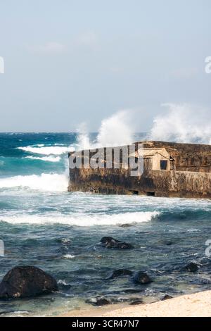 Wellen stoßen an einer felsigen Küste unter klarem Himmel gegen eine alte Steinstruktur. Phu Quy Island, Bnh Thuan, Vietnam Phu Quy Island, Bnh Thuan, Vietnam Stockfoto