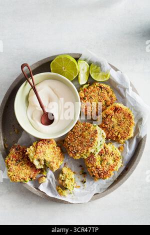 Knusprige Falafelfritter mit Joghurt-Dip und Limettenscheiben auf einem mit Pergament gefütterten Teller. Stockfoto