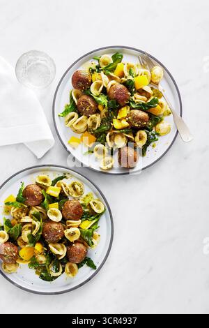 Nudelteller mit Fleischbällchen, Gemüse und gelber Paprika auf weißer Marmoroberfläche. Stockfoto