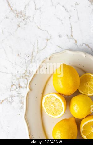 Frische Zitronen, ganz und in Scheiben geschnitten auf einem rustikalen Hintergrund Stockfoto