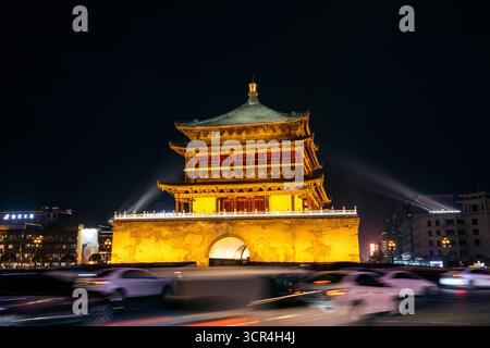 Beleuchtetes historisches Gebäude bei Nacht mit verschwommenen Autolampen vorbeiziehen. Glockenturm von Xi'an, China Stockfoto