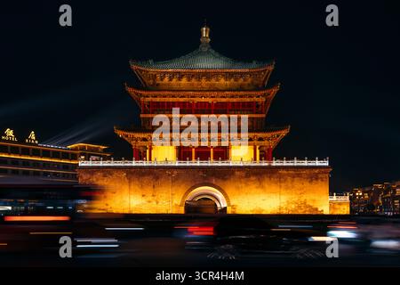 Beleuchtetes traditionelles chinesisches Gebäude bei Nacht mit verschwommenen Lichtern der Stadt. Glockenturm von Xi'an, China Stockfoto