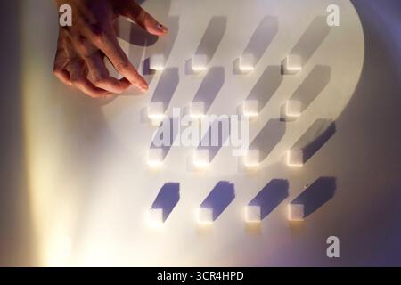 Zuckerschwürfel von Hand auf einer weißen Oberfläche mit dramatischen Schatten anordnen. Stockfoto