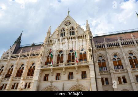 Architektonische Details der Fassade des ungarischen Parlamentsgebäudes mit ungarischen Fahnen auf dem Kossuth-Lajos-Platz in Budapest, Ungarn. Stockfoto