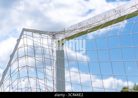 Detaillierte Ansicht der alten Fußballtorecke und des Netzes unter wolkenblauem Himmel. Stockfoto