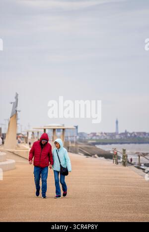Ein älterer Mann und eine ältere Frau gehen Hand in Hand entlang der Promenade in Livereys, Lancashire, Großbritannien Stockfoto