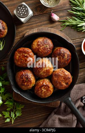 Hackschnitzel aus Schweinefleisch und Rindfleisch in gusseiserner Pfanne auf Holztisch. Draufsicht, flach Stockfoto