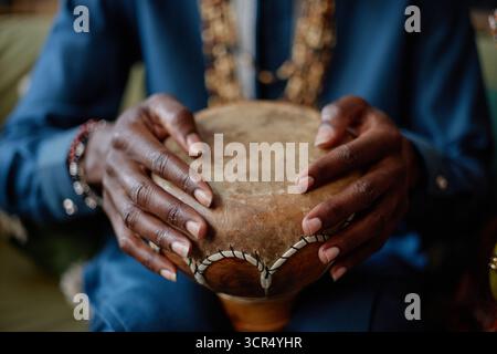 Schwarzer Mann spielt traditionelle Trommel während der Kwanzaa-Feier drinnen Stockfoto