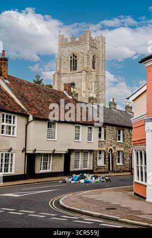 Hausmüll wurde in der Mitte einer engen Stadtstraße in der Nähe einer T-Kreuzung mit alten Häusern und einer Kirche in Suffolk, England, entsorgt Stockfoto