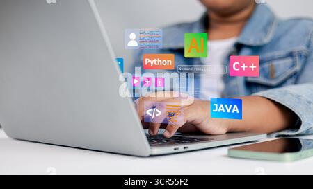 Junger Programmierer, der auf einem Laptop mit Codiersymbolen wie Python, Java, C++ und KI schreibt. Konzept der Informatik, Softwareentwicklung und Technologie le Stockfoto
