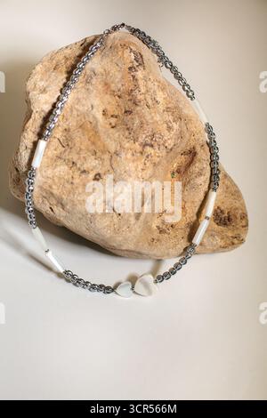 Die zarte Halskette aus Silberketten und weißen Perlen zeigt einen Herzanhänger, der elegant auf weichem Seidenstoff platziert ist und seine Schönheit und s unterstreicht Stockfoto