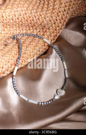 Diese Szene zeigt eine elegante Halskette aus Perlen und Anhängern auf luxuriösem Seidenstoff. Die verschiedenen Farben und Materialien erzeugen ein captiva Stockfoto