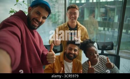 Webcam POV vier multirassische Kollegen informelles Business-Team, das Selfie-Foto macht, posiert zusammen glücklich lächelnd und zeigt Daumen nach oben lässiges Unternehmen Stockfoto