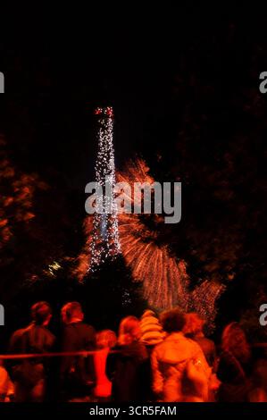 Verschwommenes Foto von Menschen, die während der Feierlichkeiten zum französischen Nationalfeiertag (Tag der Bastille am 14. Juli) ein Feuerwerk in der Nähe des Eiffelturms beobachten. Stockfoto