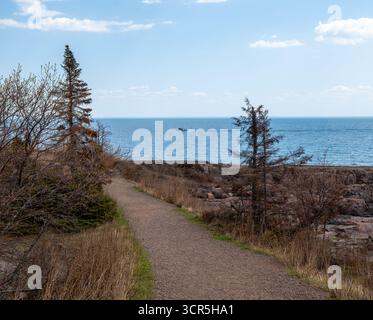Wanderweg entlang der North Shore of Lake Superior in Two Harbors, Minnesota, und ein Boot auf dem blauen Wasser, an einem Frühlingstag. Stockfoto