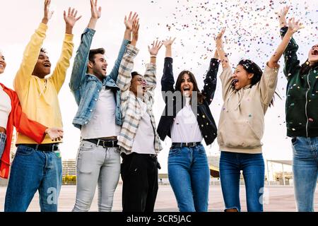 Eine Gruppe verschiedener junger Freunde feiert zusammen und wirft Konfetti auf die Party Stockfoto