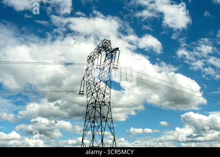 Hochspannungsleitungen gegen einen hellblauen Himmel mit verstreuten Wolken, Puy de Dome, Auvergne Rhone Alpes, Frankreich Stockfoto