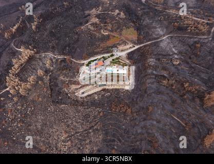 Aus der Vogelperspektive eines einsamen Hauses mit Pool inmitten einer schroffen, verbrannten Landschaft, ein Zeugnis des jüngsten Zornes der Natur, AVO, Olivera do Hospital, Portugiesisch Stockfoto
