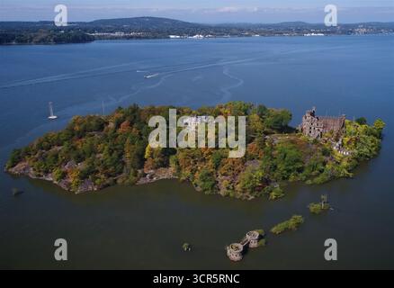 Aus der Vogelperspektive auf eine Insel mit herbstlichen Bäumen, historischen Ruinen und einem einsamen Turm inmitten der ruhigen Gewässer, Hudson, New York, USA. Stockfoto