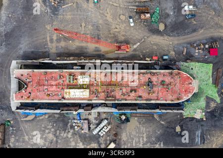 Der Blick aus der Vogelperspektive auf das rot gedeckte Schiff ragt stark gegen die graue Umgebung, mit einem Kran über dem Deck des Schiffes, Hudson, New York, USA. Stockfoto