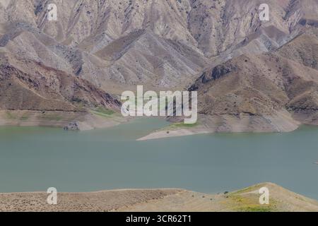 Blick auf den ruhigen See, eingebettet in zerklüftete, sonnenverwöhnte Berge, mit trockenem Erdreich im Kontrast zum Wasser, Azat Reservoir, Provinz Ararat, Armen Stockfoto