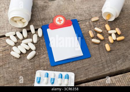 Verschiedene Medikamente und ein leeres Rezeptpad auf einem Holztisch Stockfoto