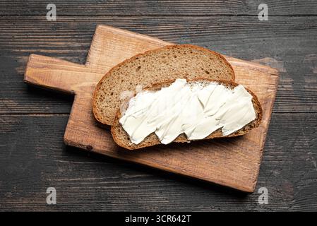 Butter und Brot zum Frühstück auf hölzernem Hintergrund, Blick von oben. Sauerteigscheiben mit Bio-Butter. Stockfoto