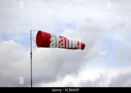 Rot-weiß gestreifter Windsockenkegel zeigt Windrichtung und Windgeschwindigkeit von etwa 15 Knoten auf dem Flugplatz in Nahaufnahme an Stockfoto