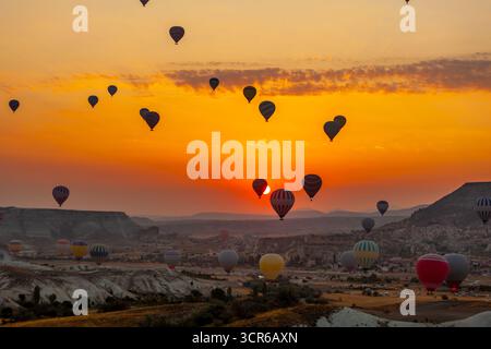 Heißluftballon fliegt über felsige Landschaft bei Sonnenaufgang in Kappadokien. Türkei Stockfoto